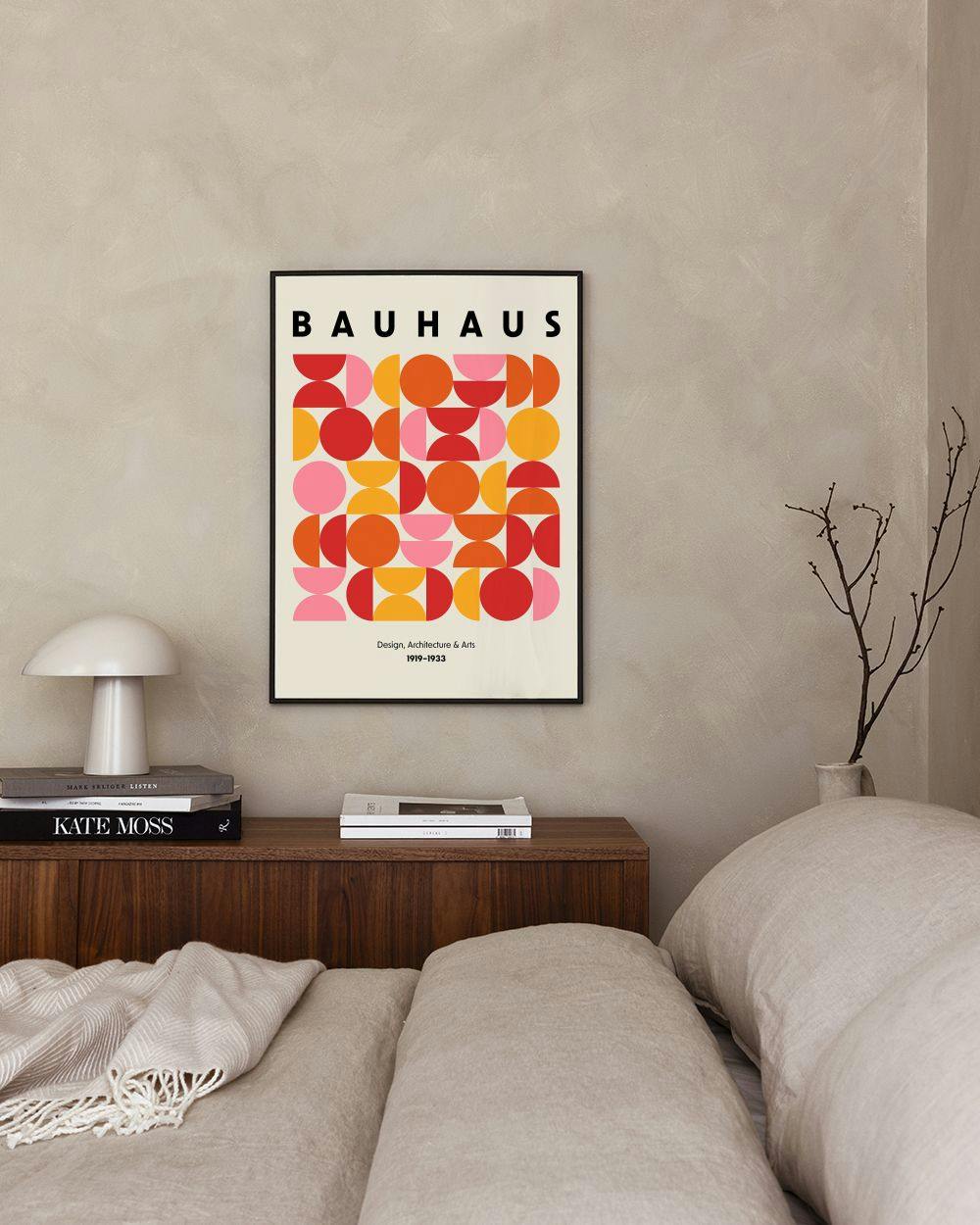 Affiche Bauhaus avec formes géométriques colorées, suspendue au-dessus dune table de chevet en bois dans une chambre.