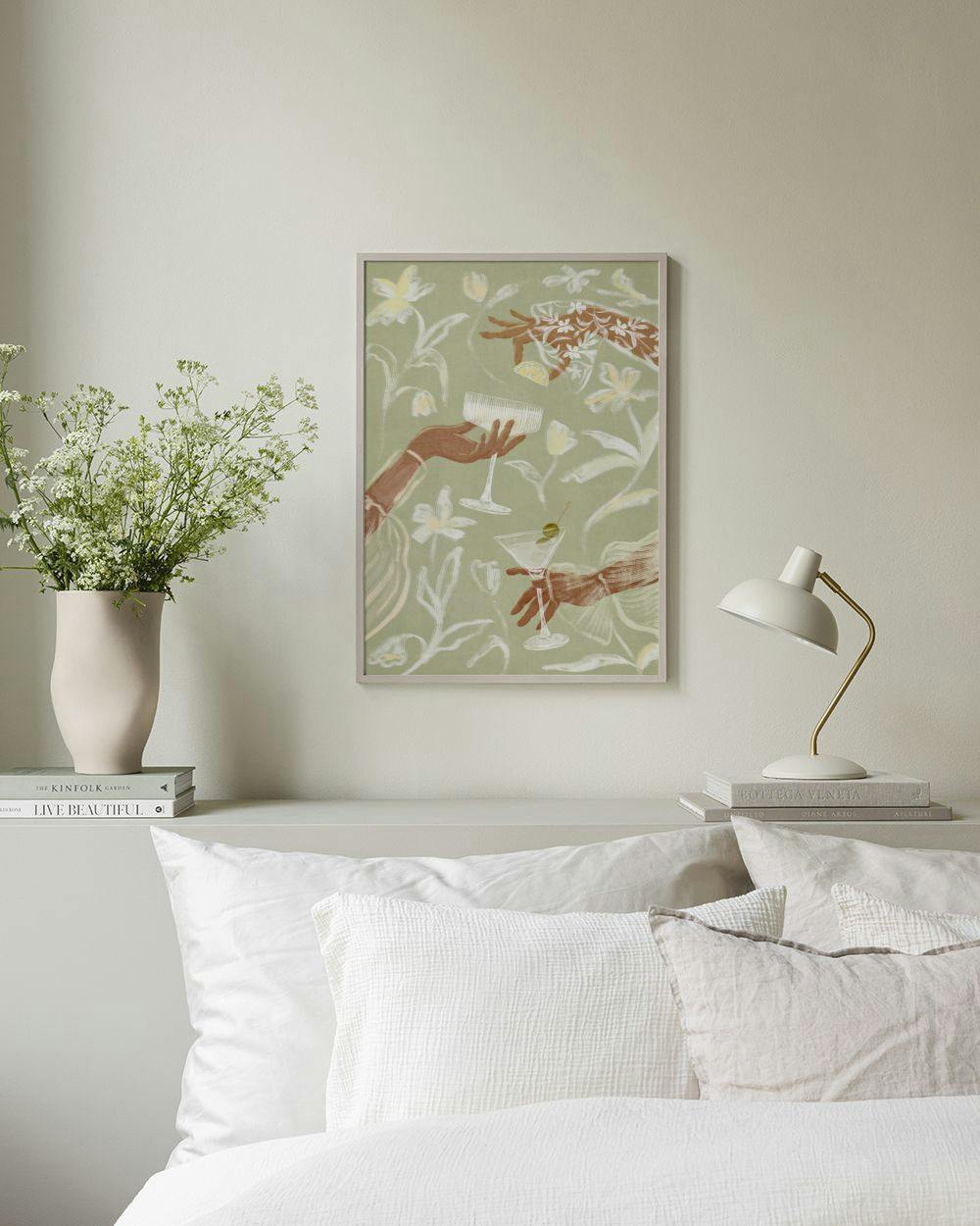 Affiche avec deux mains tendant des cocktails sur fond floral vert pâle, affichée au-dessus dun lit.