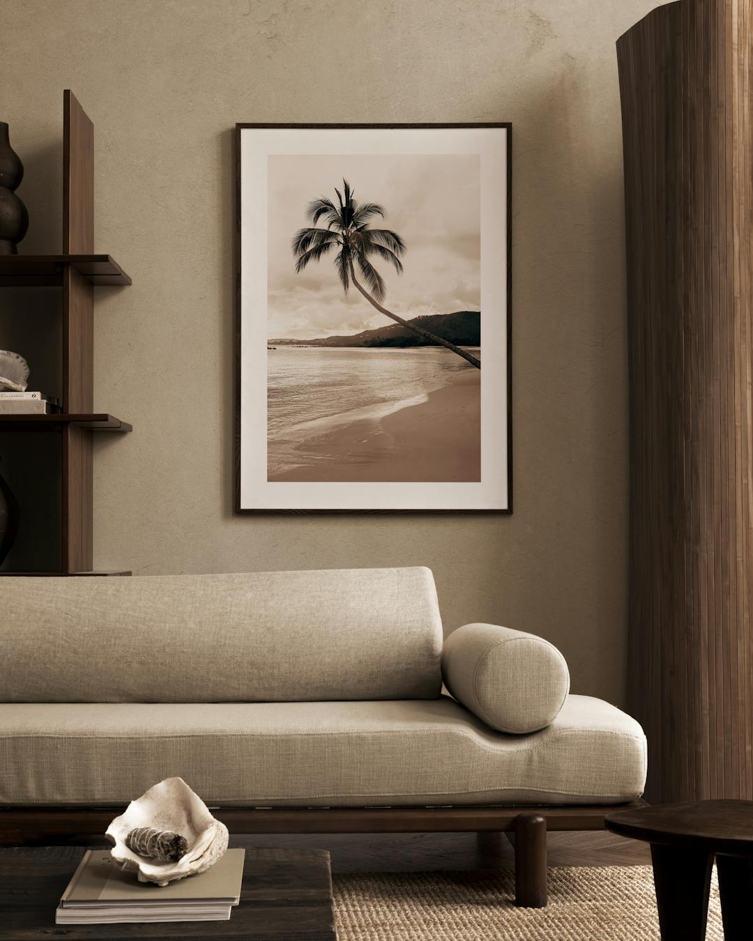 Affiche sépia dun palmier sur une plage tropicale, accrochée au-dessus dun canapé beige dans un salon moderne.
