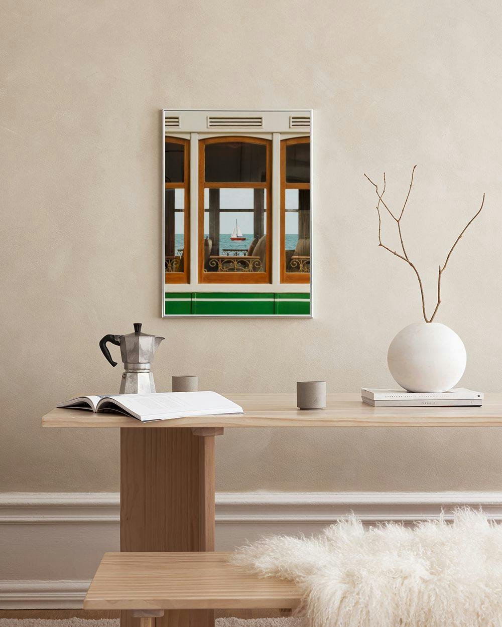 Affiche avec vue sur la mer depuis une fenêtre de tramway, un voilier rouge à lhorizon, suspendue au-dessus dune table en bois c