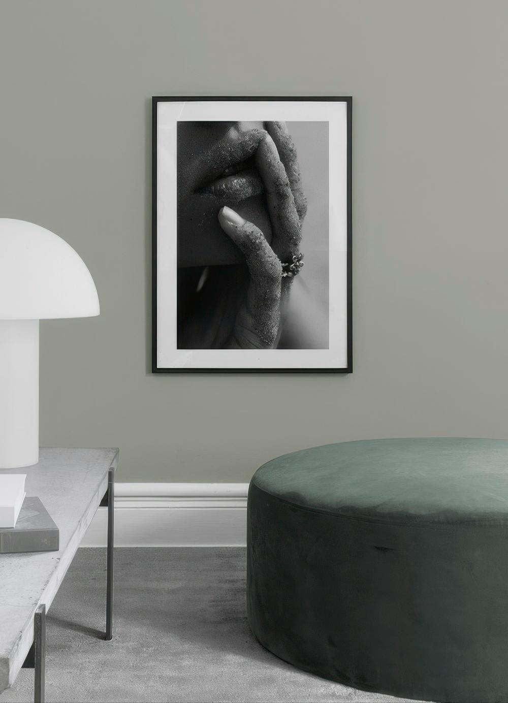 Affiche en noir et blanc dune main et de lèvres couvertes de sable, accrochée dans un salon moderne.