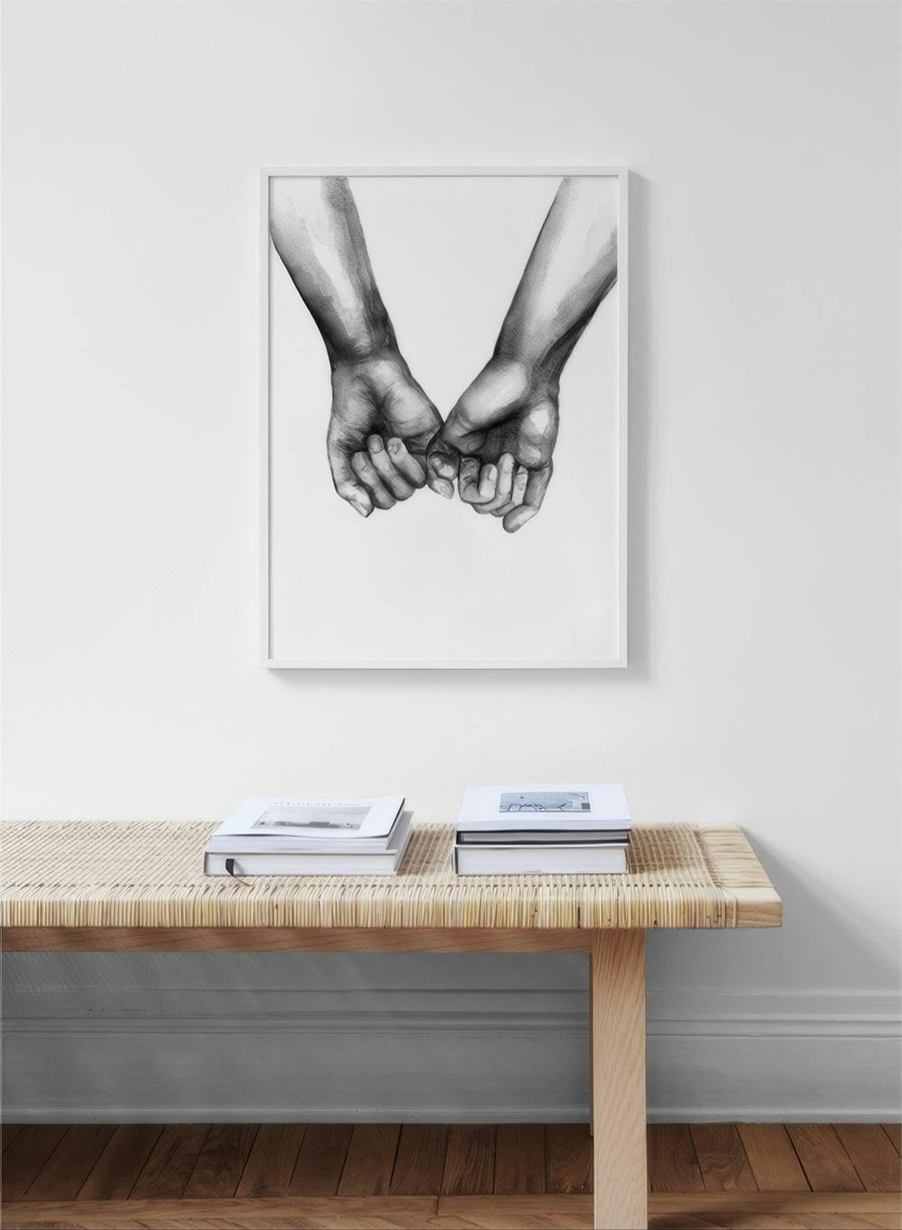 Affiche en noir et blanc de deux mains se tenant par le petit doigt, accrochée au-dessus dun banc en bois avec des livres.