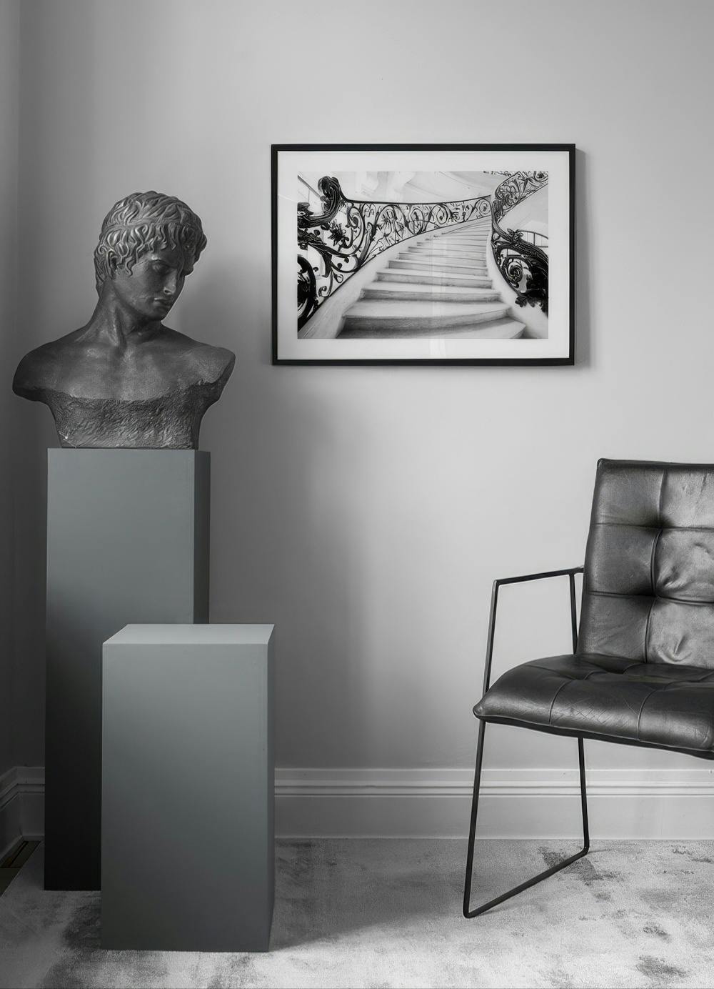 Affiche en noir et blanc d’un escalier en colimaçon avec une rampe en fer forgé, accrochée dans un intérieur moderne.