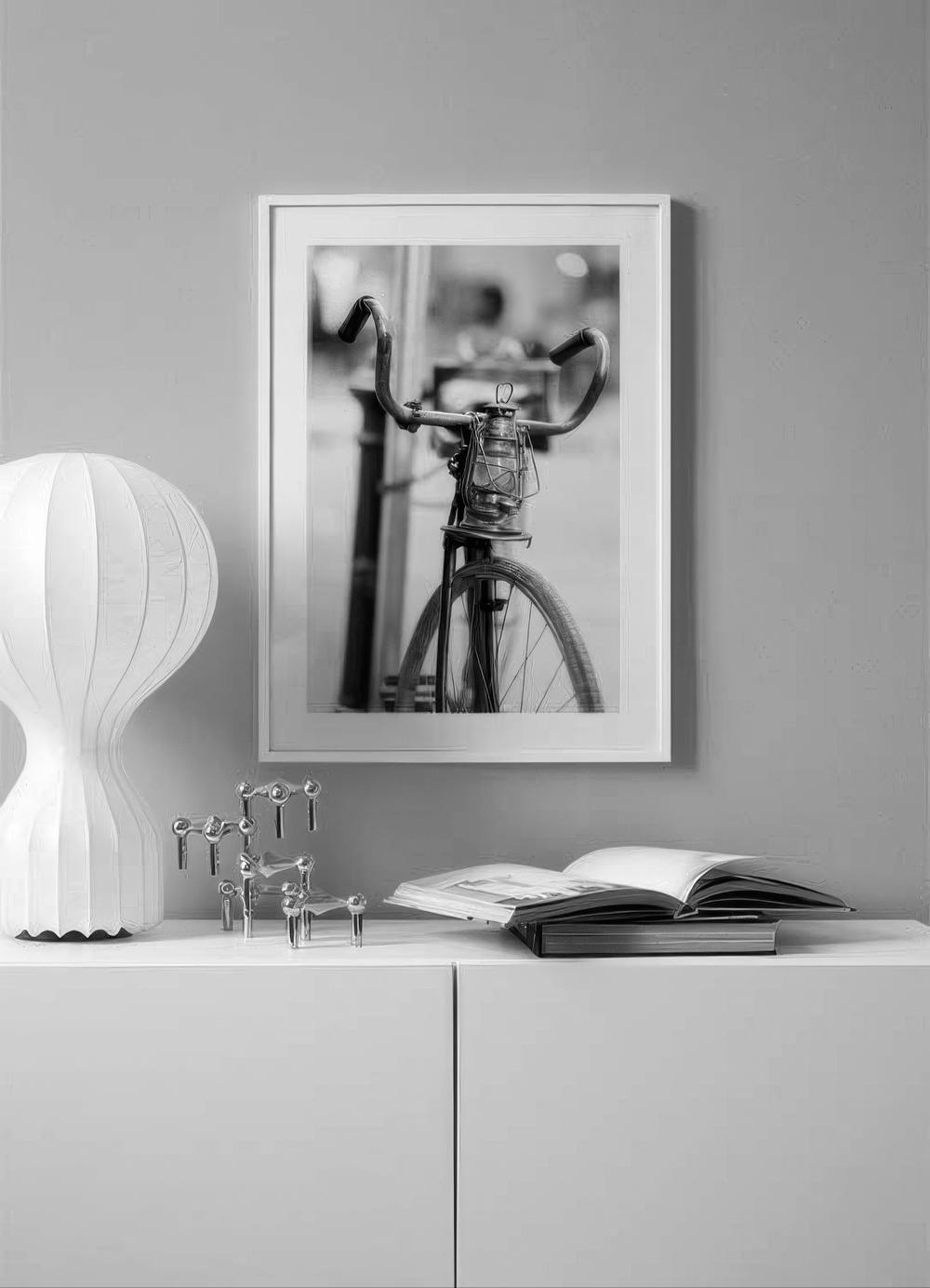 Affiche en noir et blanc dun vélo avec lanterne, suspendue au-dessus dun meuble blanc dans un salon.