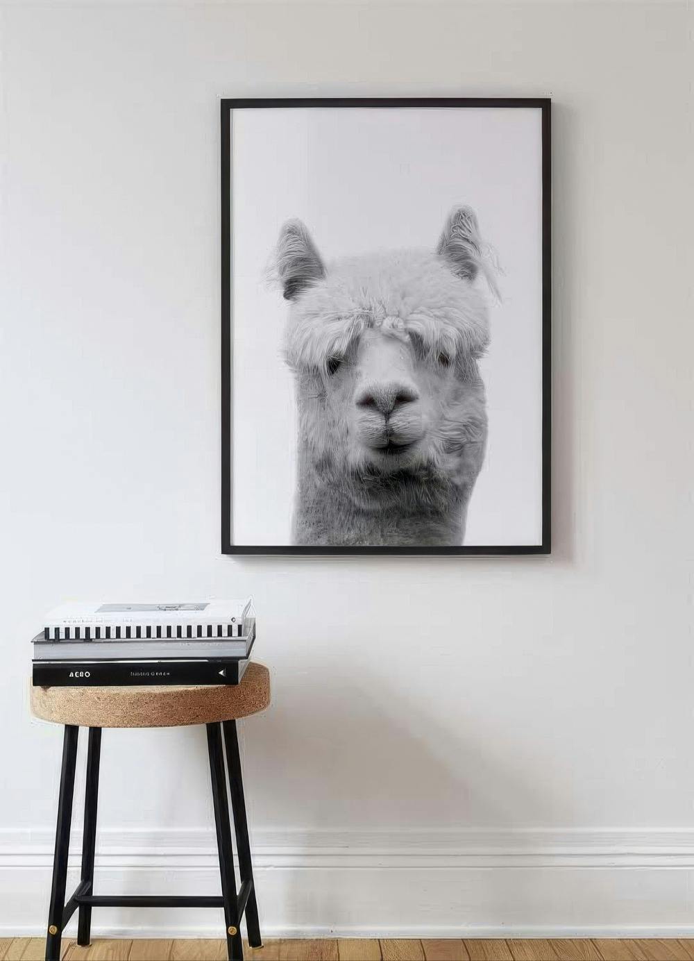 Affiche en noir et blanc dun alpaga au pelage hirsute, suspendue au-dessus dun tabouret avec des livres.