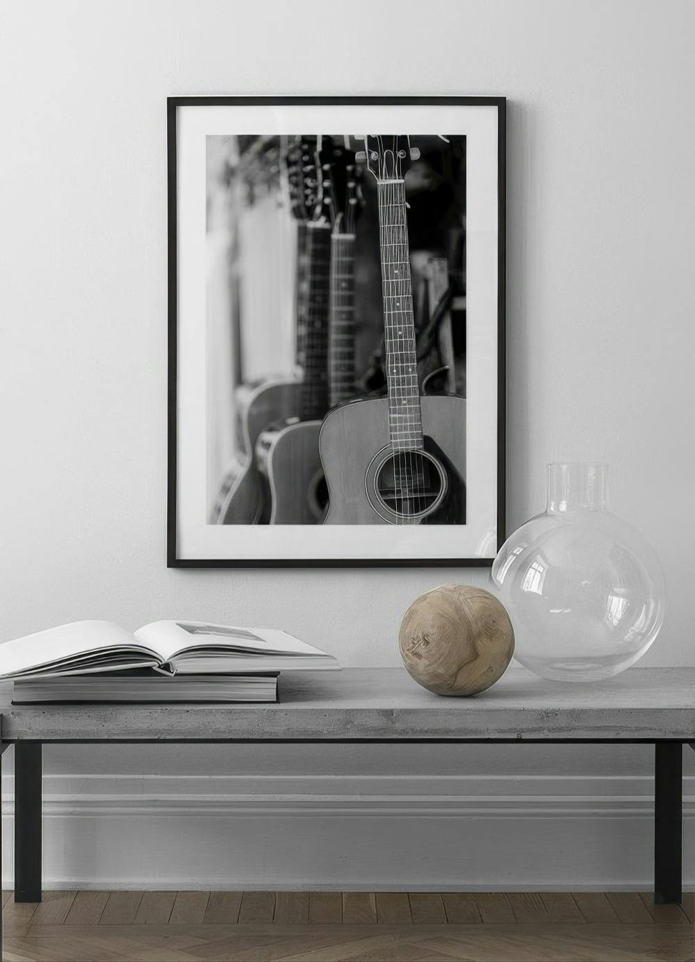 Affiche en noir et blanc de guitares acoustiques, accrochée au-dessus dun banc en béton dans un salon moderne.
