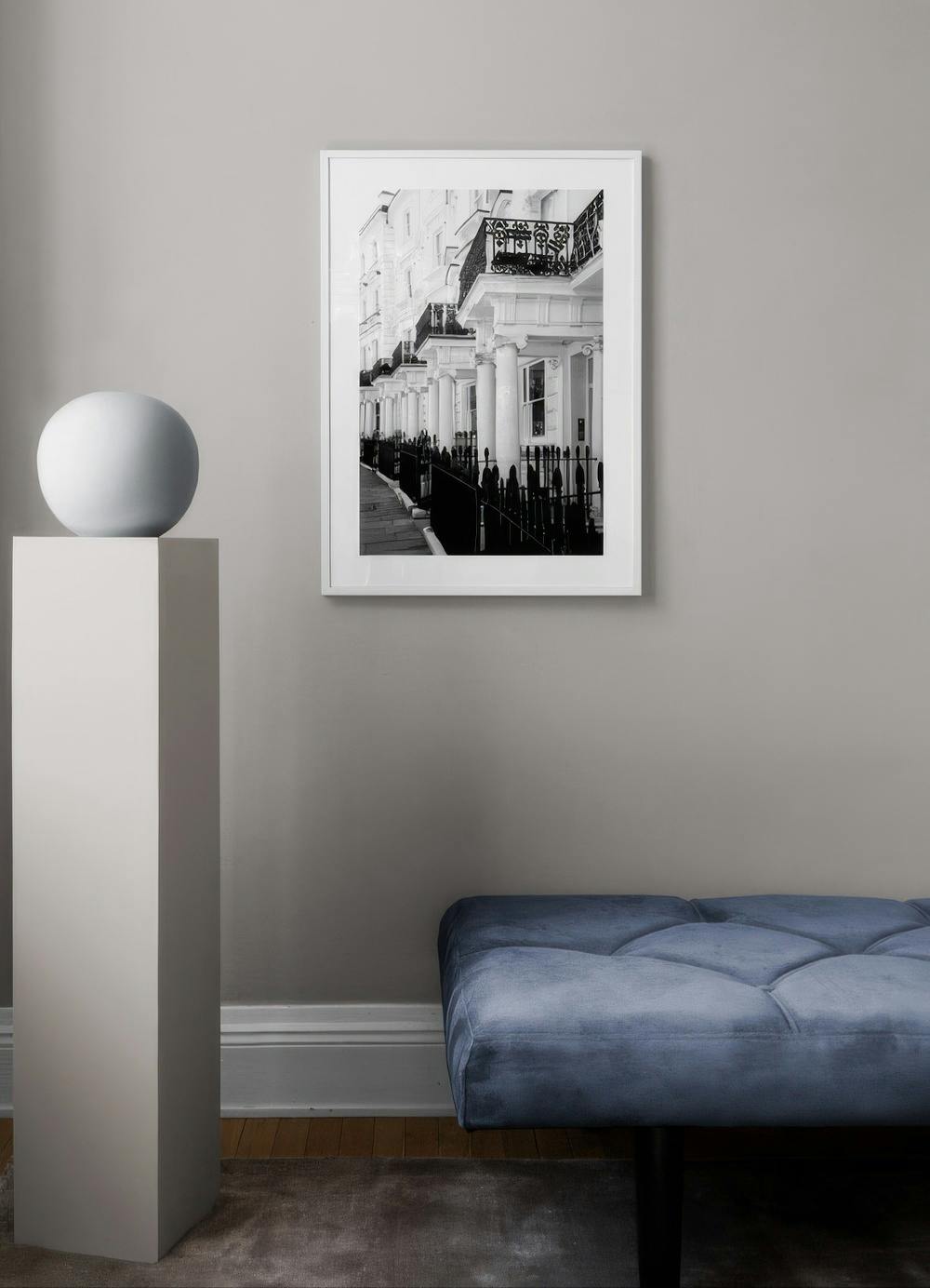 Affiche en noir et blanc de maisons urbaines alignées avec des balcons, au-dessus dun banc bleu.