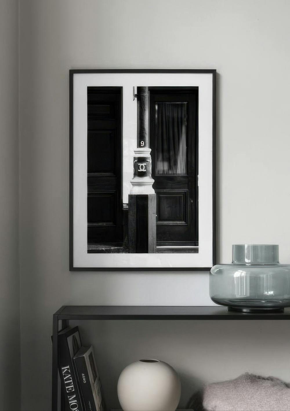 Affiche en noir et blanc dun lampadaire avec le numéro 9 et un logo, devant une porte sombre, accrochée au-dessus dune étagère m