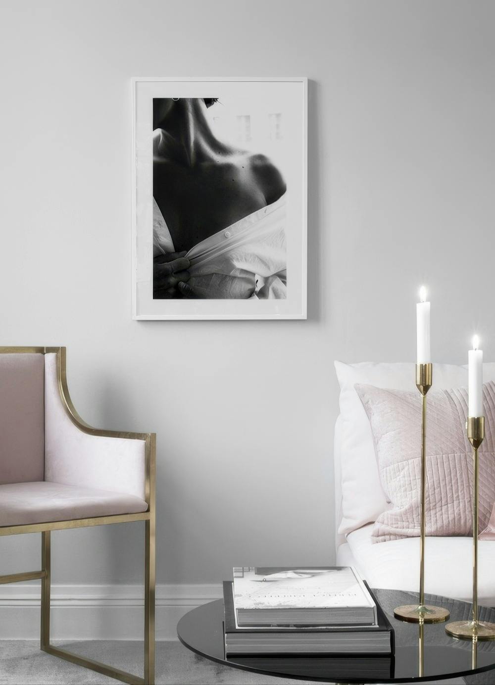 Affiche noir et blanc dun torse féminin en chemise ouverte, accrochée dans un salon moderne avec fauteuil et table basse.