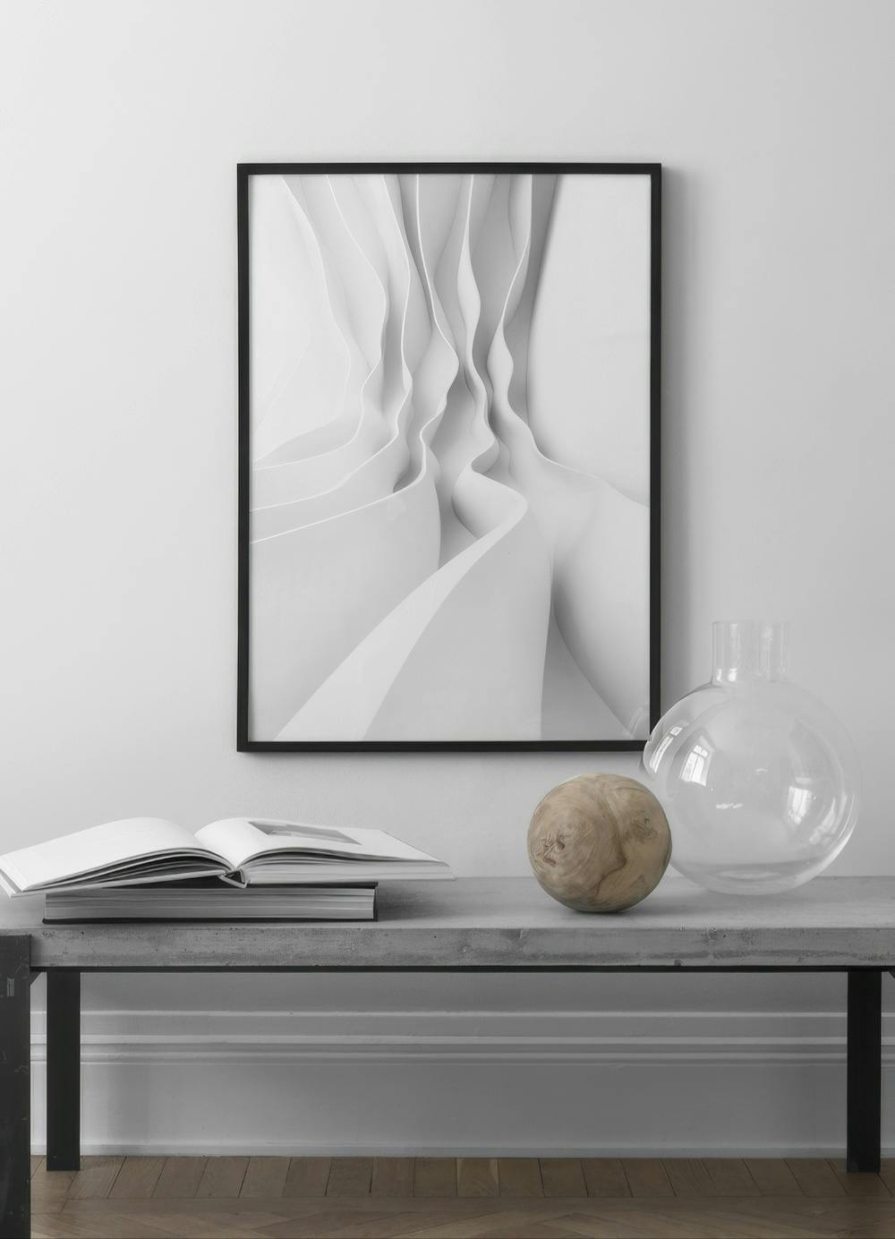 Affiche noir et blanc avec des vagues abstraites et des formes fluides sur un mur blanc, au-dessus dun banc en béton.