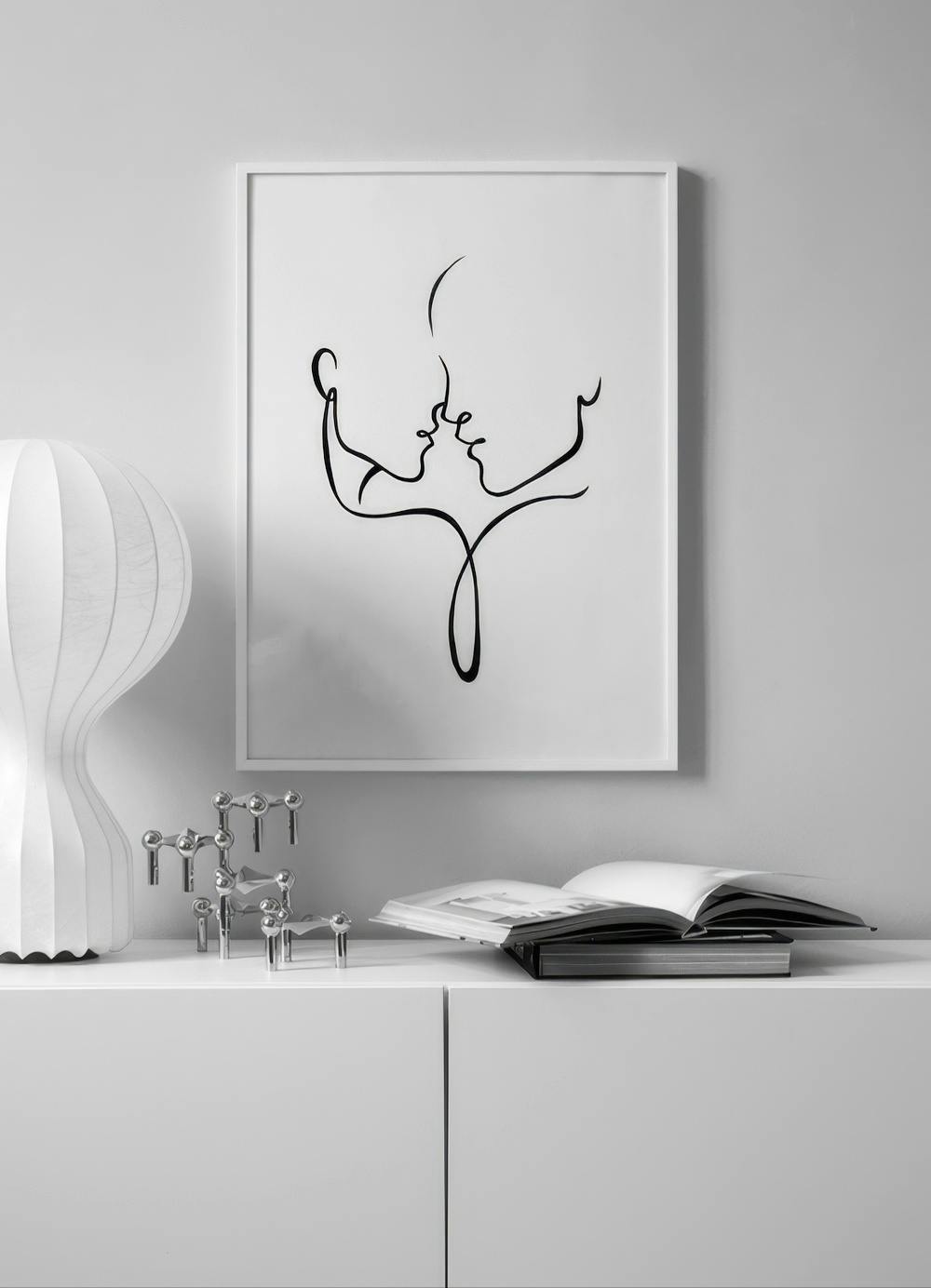 Affiche minimaliste de deux visages de profil enlacés par une ligne noire, exposée dans un salon moderne.