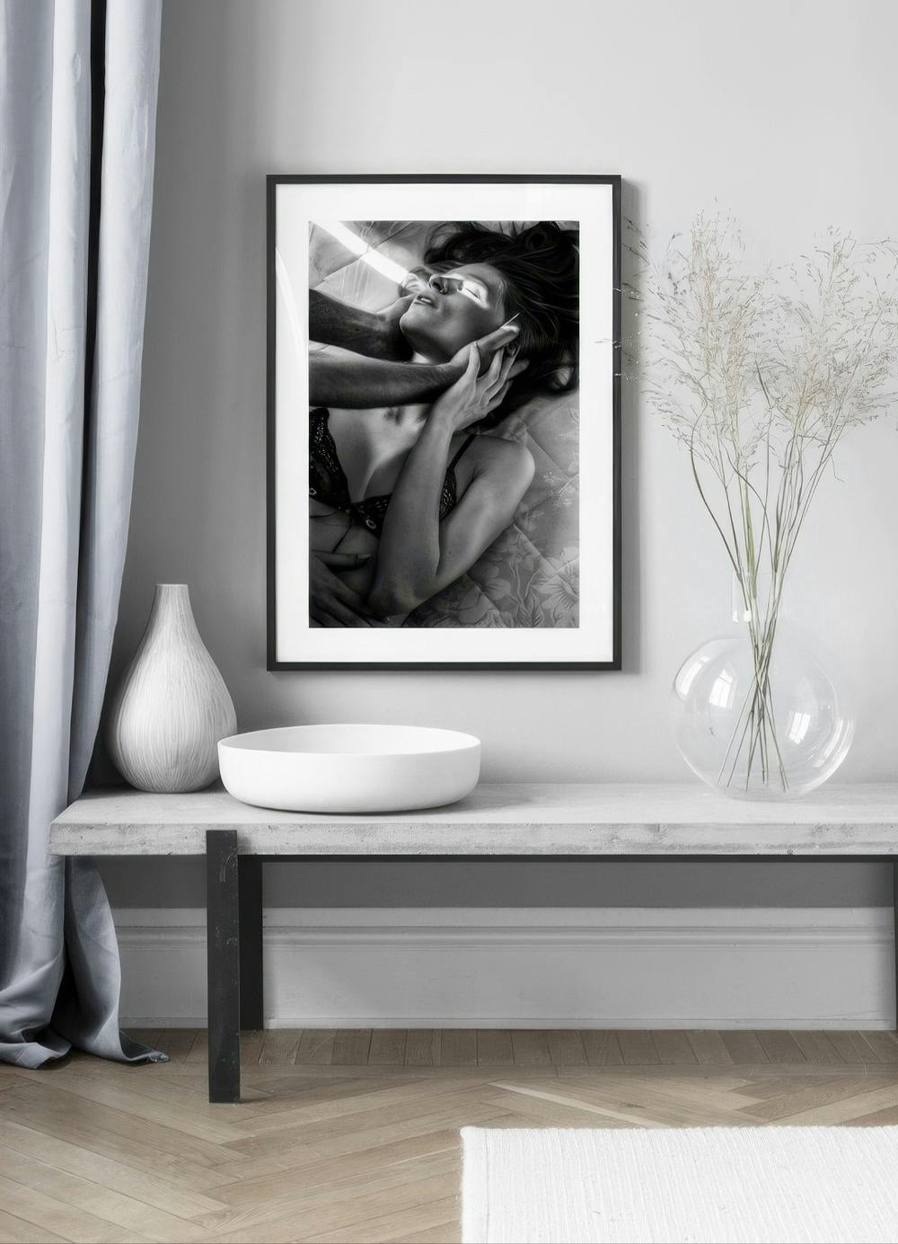 Affiche photo femme et mains dhomme en noir et blanc, affichée au-dessus dun banc en béton.