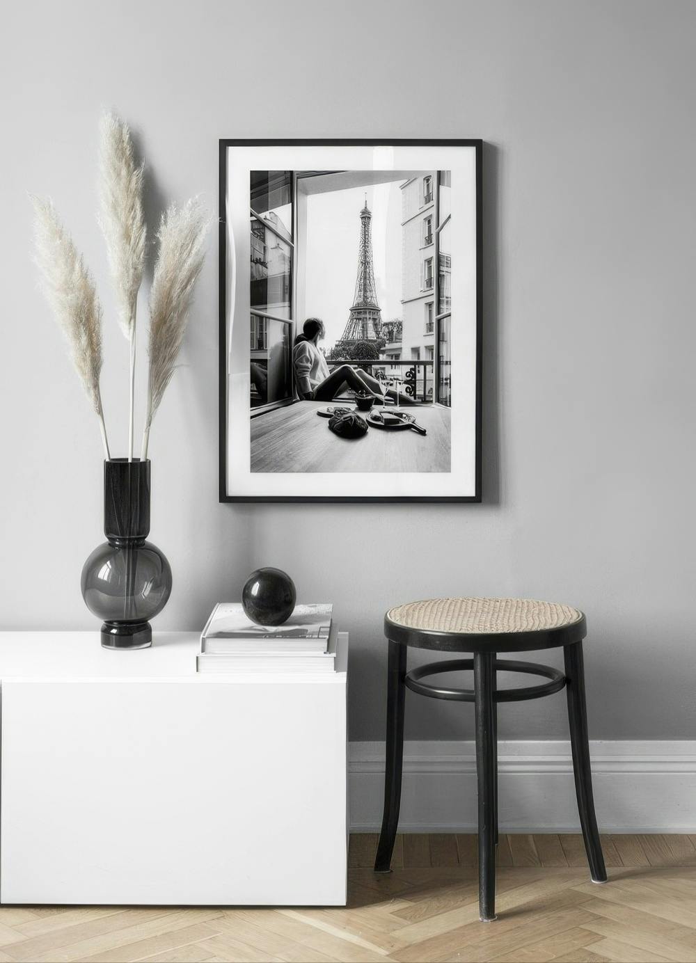 Affiche noir et blanc dune personne regardant la Tour Eiffel depuis un balcon, affichée dans un intérieur moderne.