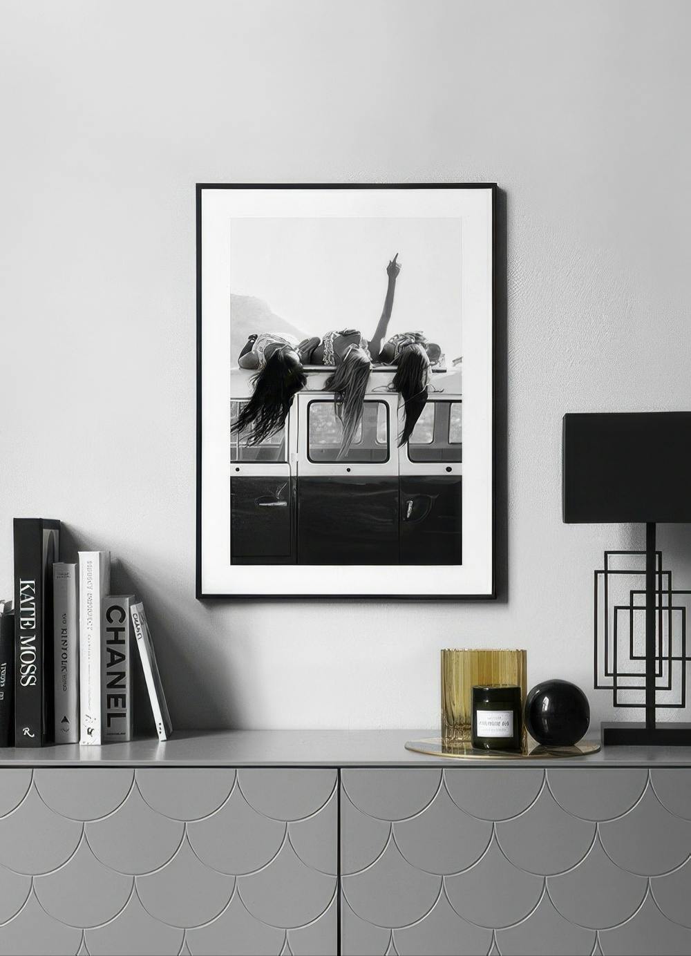 Affiche noir et blanc de trois femmes allongées sur le toit dun van, exposée au-dessus dun buffet gris.