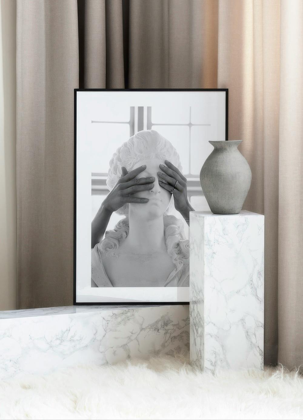 Affiche en noir et blanc dun buste de statue avec des mains couvrant les yeux, posée au sol dans une ambiance neutre.
