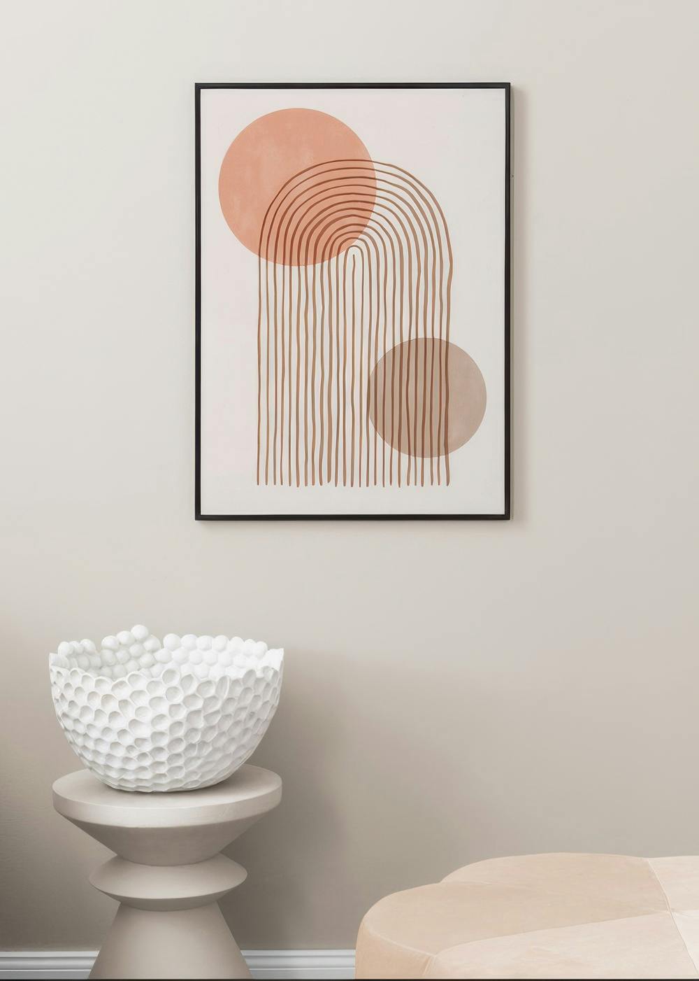 Affiche abstraite avec des arcs et des lignes verticales marron, et des cercles saumon, sur un mur clair dans un salon.
