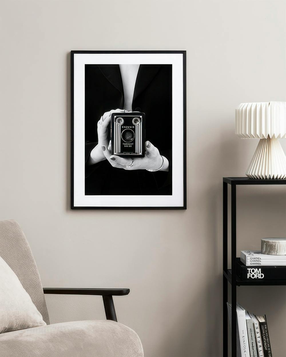 Affiche photo en noir et blanc dune femme tenant un appareil photo vintage, accrochée dans un salon moderne.