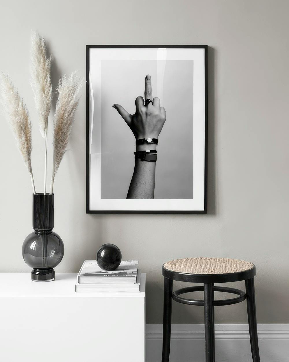 Affiche noire et blanche dune main faisant un doigt dhonneur, affichée dans un intérieur moderne.