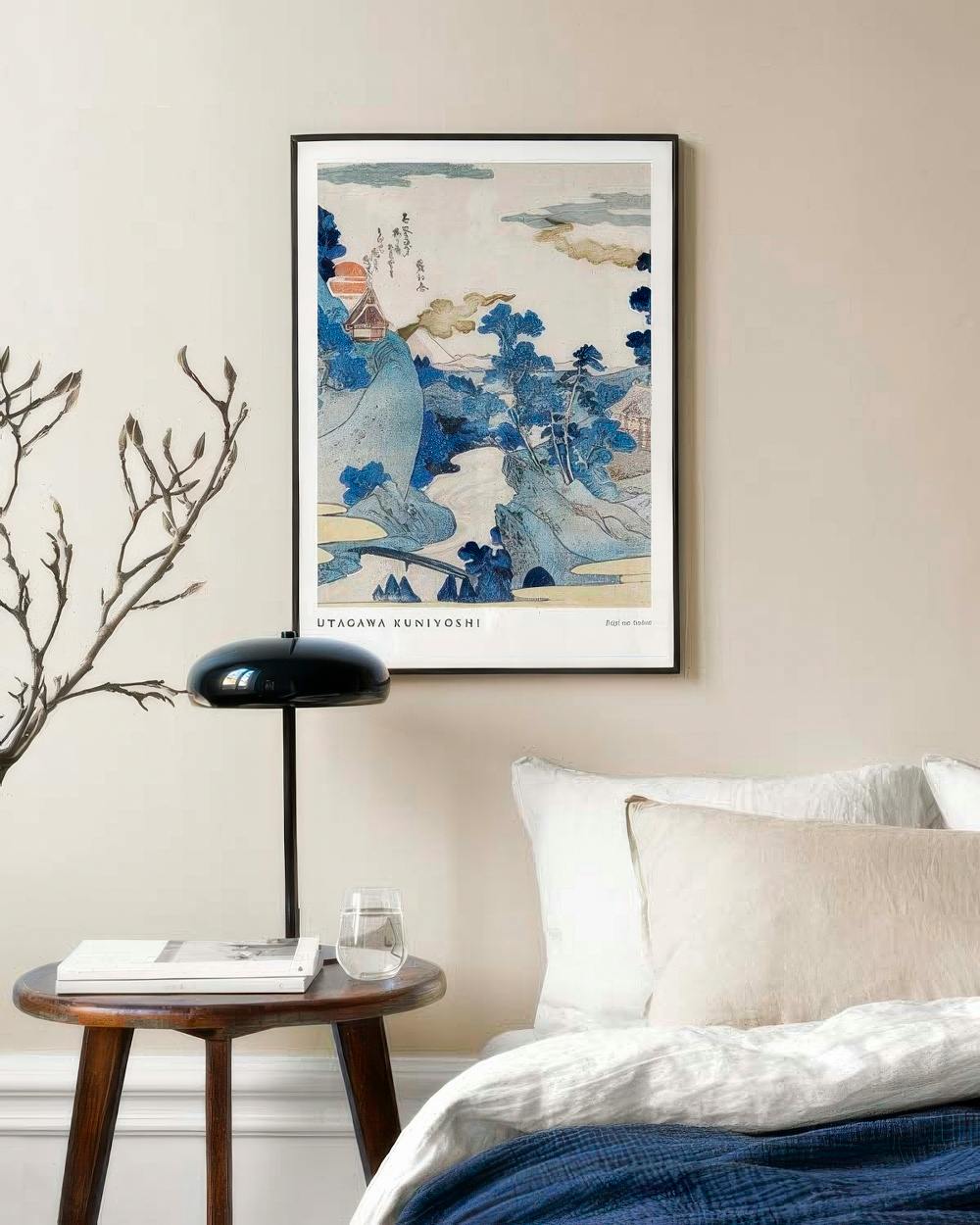 Affiche Utagawa Kuniyoshi représentant un paysage japonais en bleu, suspendue au-dessus dune table de chevet avec un livre, une 