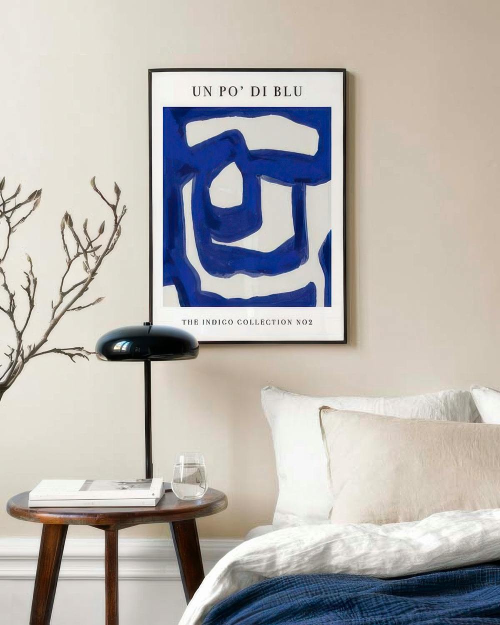 Affiche abstraite bleue et blanche avec des formes organiques, suspendue dans une chambre moderne au-dessus dune table de chevet