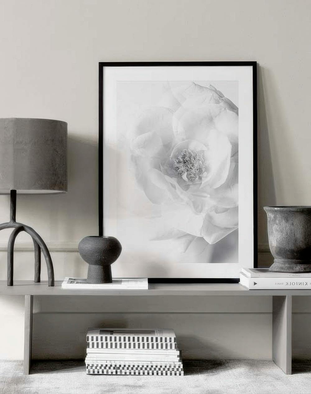 Affiche dune fleur blanche aux pétales délicats, posée sur un banc gris clair avec lampe et vase.