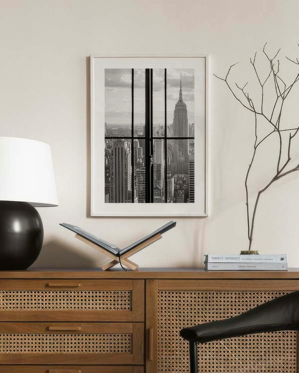 Affiche en noir et blanc de lEmpire State Building encadré, accrochée au-dessus dun buffet en bois.