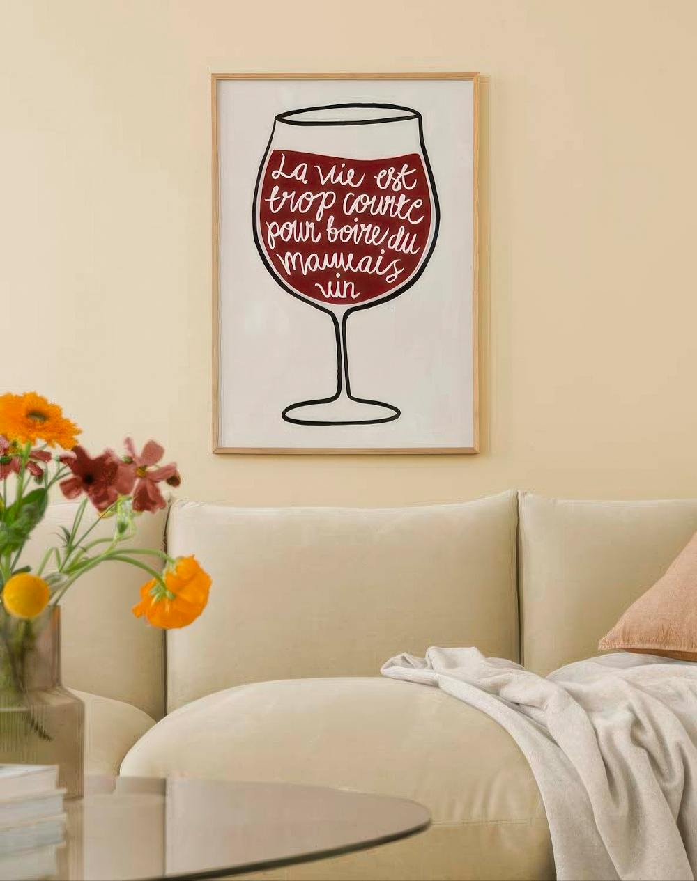 Affiche avec un verre de vin rouge et linscription La vie est trop courte pour boire du mauvais vin, au-dessus dun canapé beige.