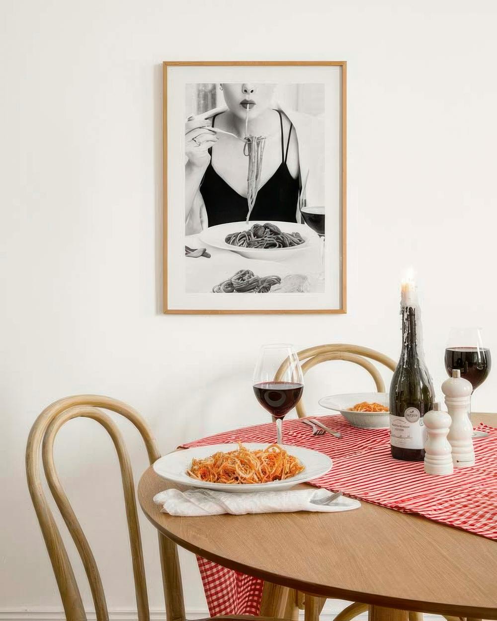 Affiche noire et blanche dune femme mangeant des pâtes, suspendue au-dessus dune table avec un dîner italien.