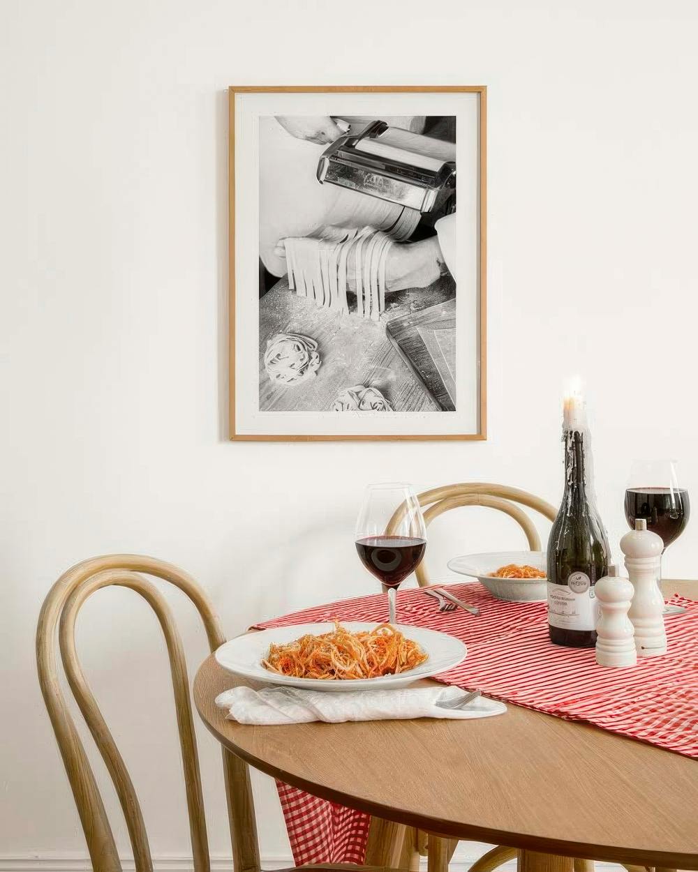 Affiche noir et blanc de fabrication de pâtes fraîches, suspendue au-dessus dune table avec des plats de pâtes.