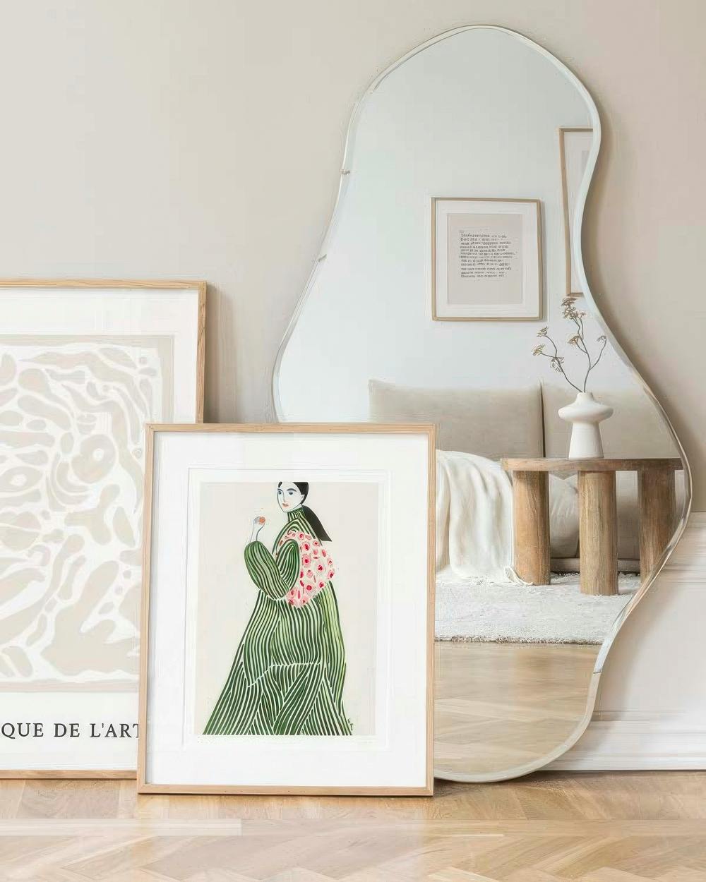 Affiche dune femme en robe rayée verte avec un sac rose, posée sur un parquet, devant un miroir ondulé.