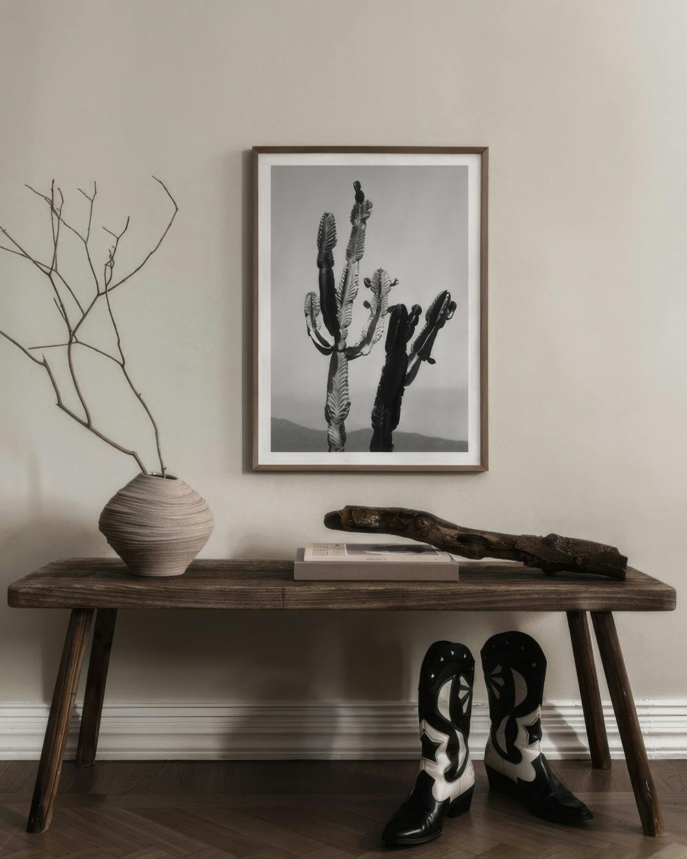 Affiche photo en noir et blanc de cactus saguaro, suspendue au-dessus dun banc en bois avec des bottes de cowboy.