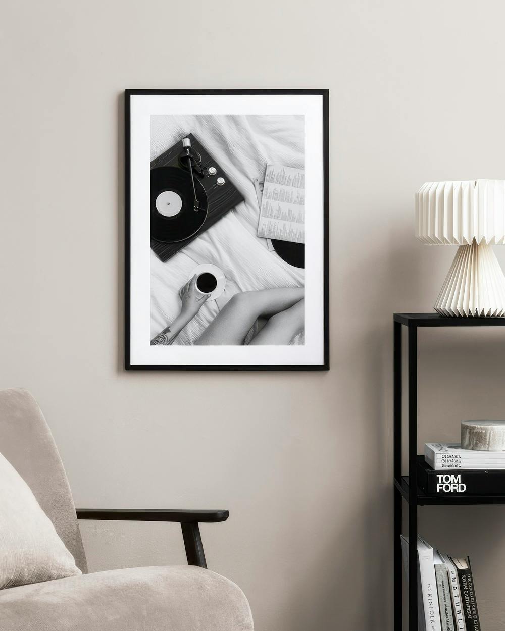 Affiche noir et blanc d’une platine vinyle, d’une tasse de café et de jambes, accrochée dans une chambre moderne.