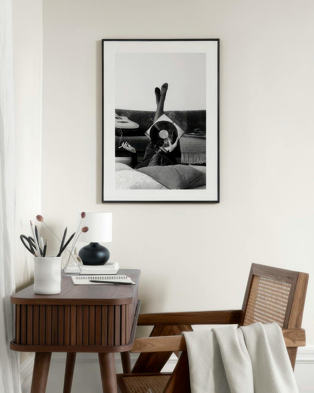 Affiche noir et blanc de personne allongée sur un canapé, tenant un disque vinyle devant son visage, accrochée dans une chambre 