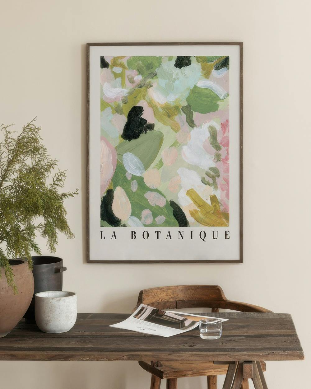 Affiche La Botanique aux formes abstraites vertes, roses et noires, accrochée au-dessus dun bureau en bois rustique.
