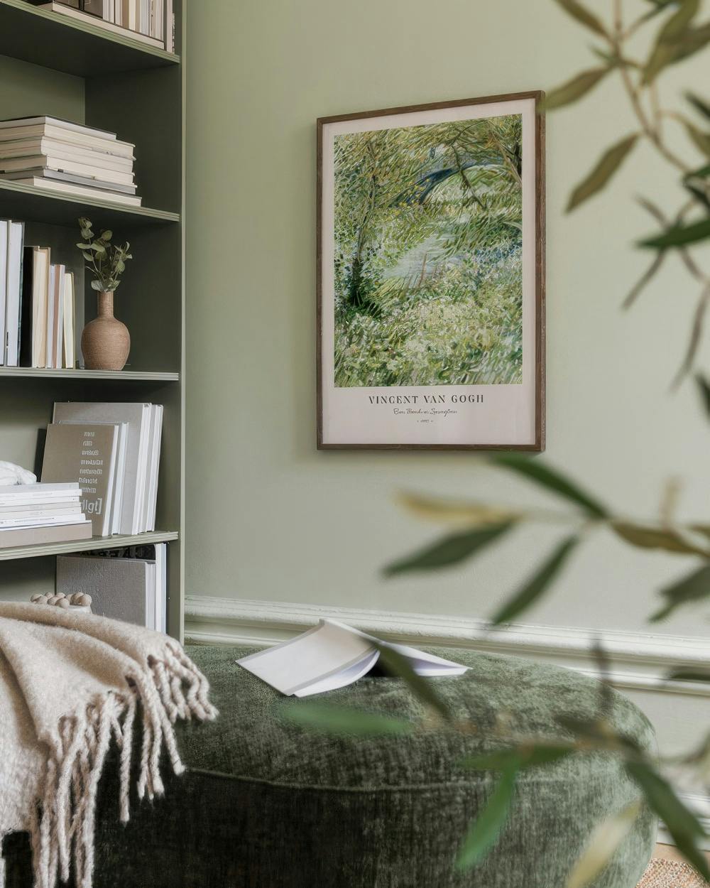 Affiche du tableau de Van Gogh Sous-bois dans un salon aux murs verts avec une bibliothèque et un pouf.