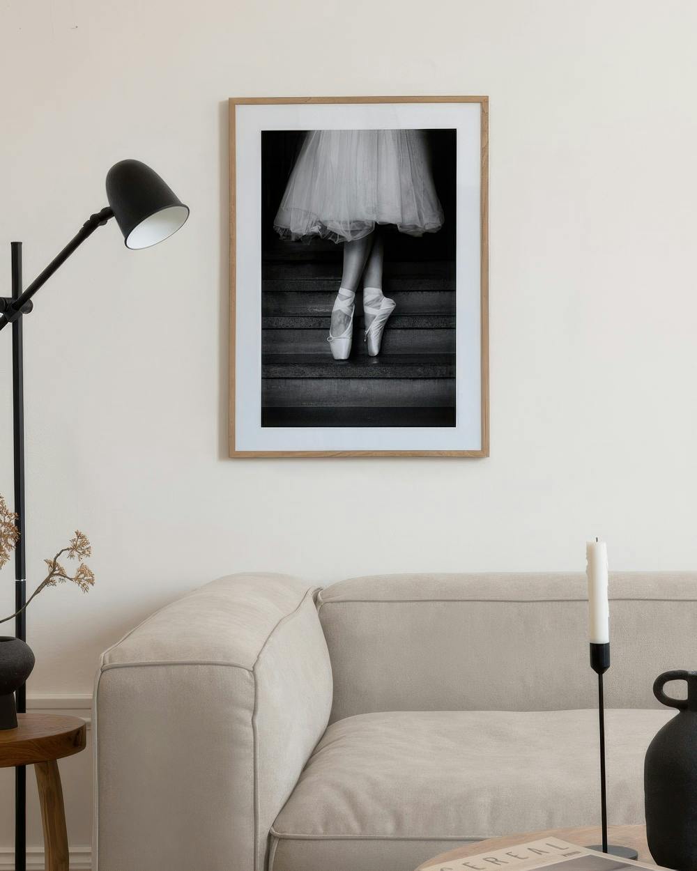 Affiche noir et blanc de pointes de ballerine et tutu sur des escaliers, exposée au-dessus dun canapé beige.