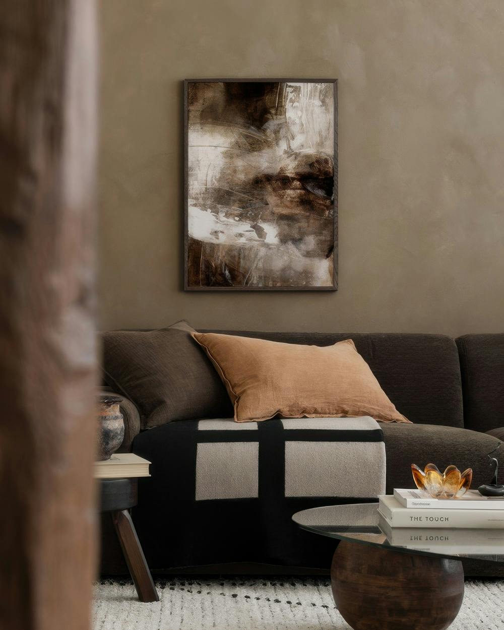 Affiche abstraite tons bruns, blancs et noirs, accrochée au-dessus dun canapé marron dans un salon moderne.