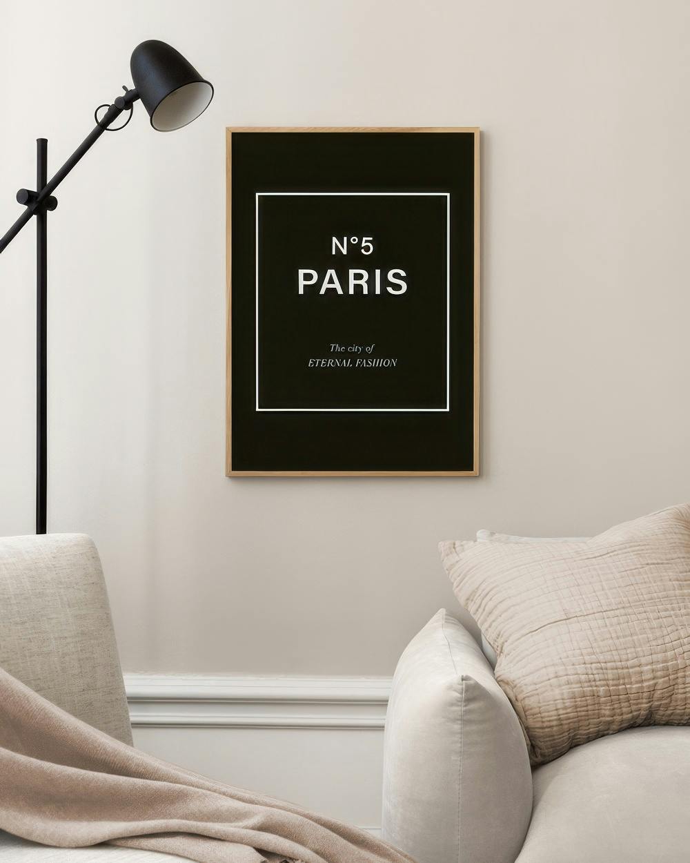 Affiche noire avec les mots N°5 PARIS The city of ETERNAL FASHION en blanc, accrochée au mur dun salon moderne.