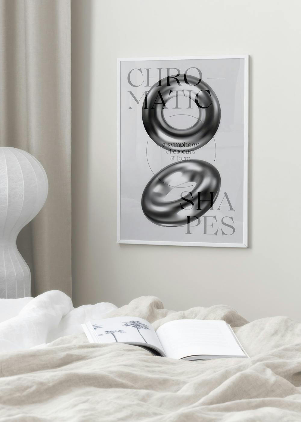 Affiche Chromatic Shapes avec des formes 3D grises et texte, accrochée au-dessus dun lit avec un livre ouvert.