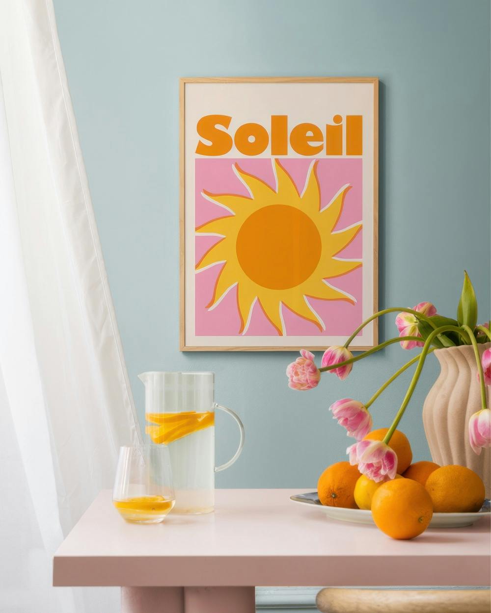 Affiche Soleil avec un soleil jaune et orange sur fond rose, accrochée dans une chambre lumineuse.