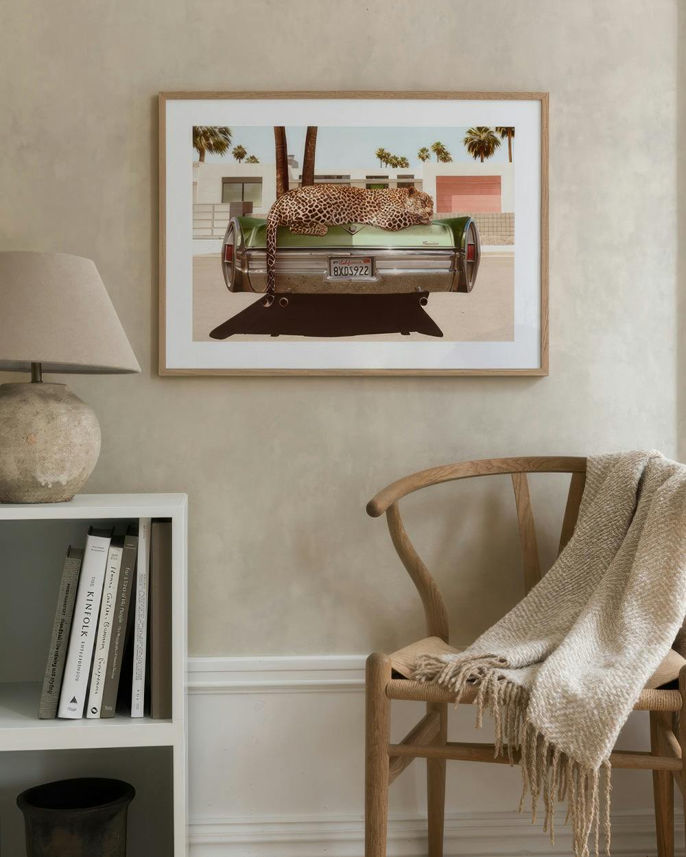 Affiche dun léopard allongé sur une voiture verte, accrochée au-dessus dune étagère et dune chaise en bois.