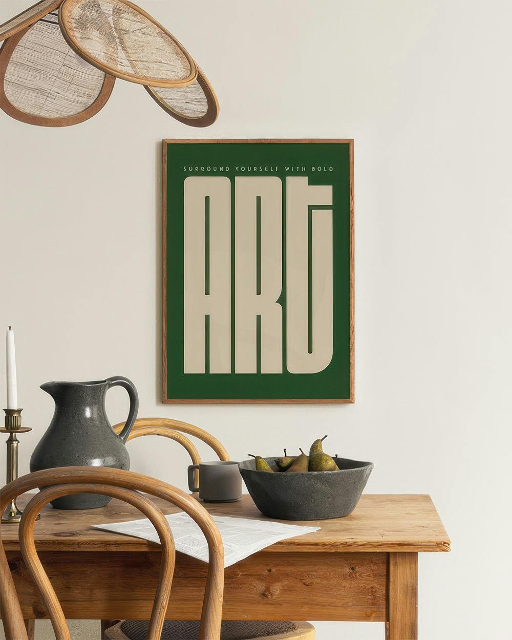 Affiche verte avec le mot ART en lettres crème, accrochée au-dessus dune table en bois avec une cruche et des poires.