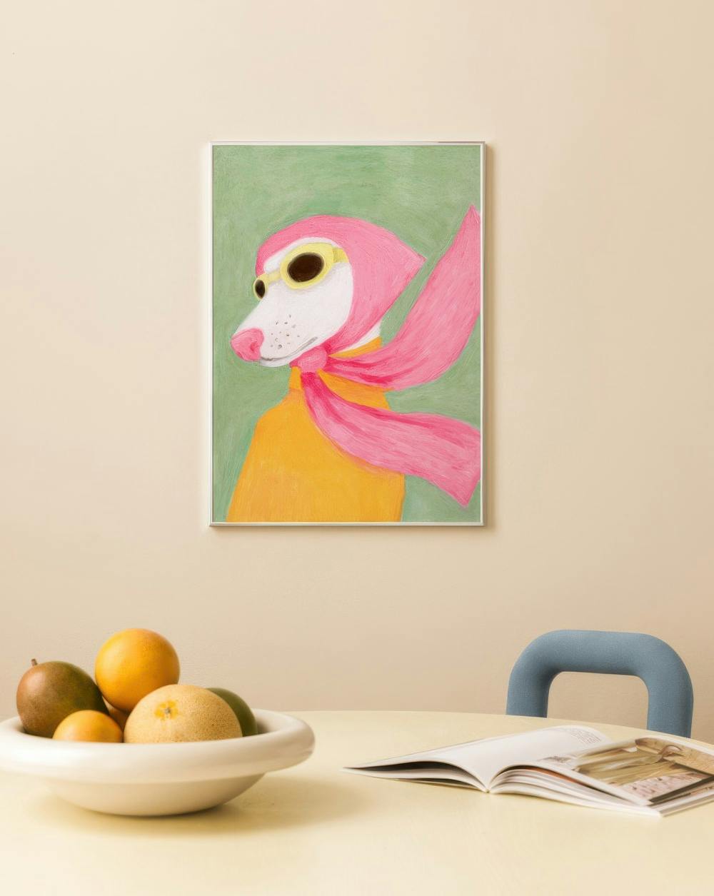 Affiche dun chien blanc avec des lunettes et un foulard rose, accrochée au-dessus dune table avec des fruits.