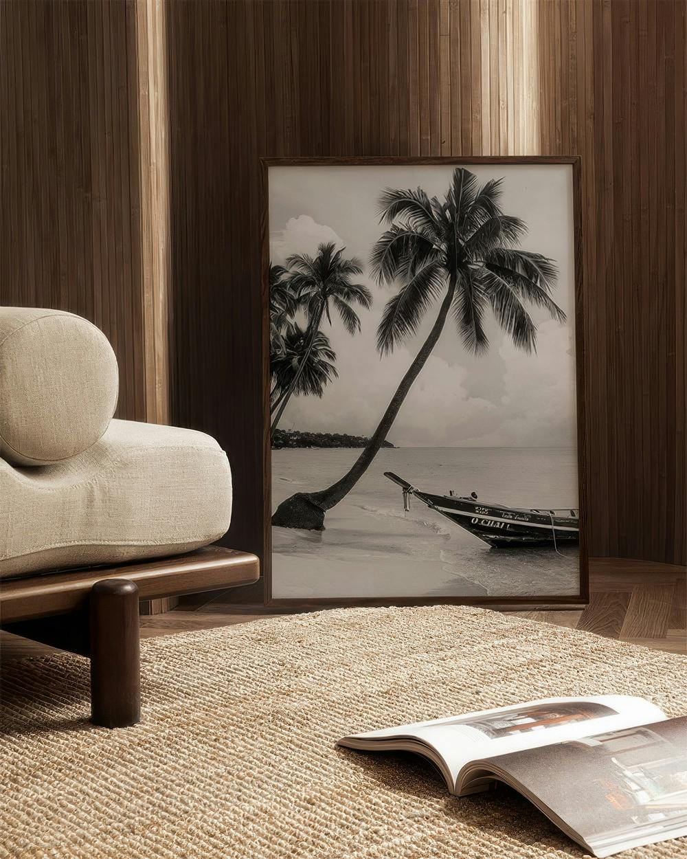 Affiche noir et blanc d’un palmier courbé sur une plage avec un bateau, posée au sol dans un salon moderne.
