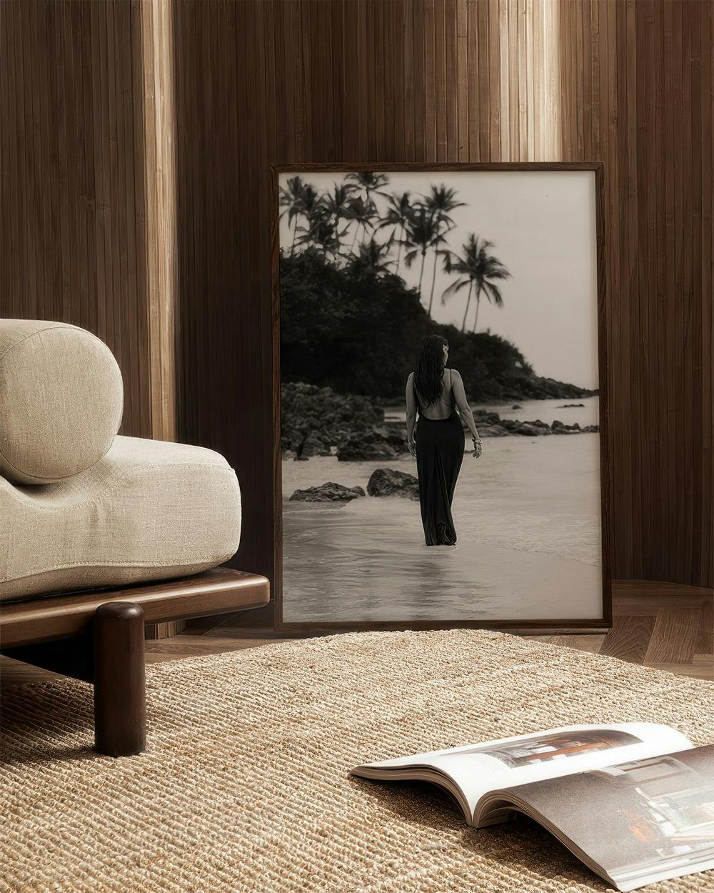 Affiche noir et blanc dune femme marchant dans leau sur une plage tropicale, posée dans un salon moderne.