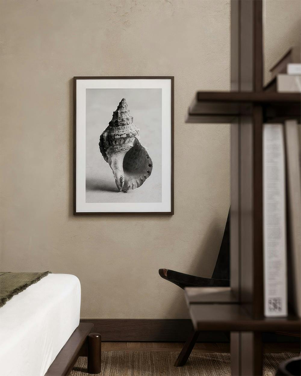 Affiche en noir et blanc dun coquillage spiralé, accrochée dans une chambre au-dessus dun lit.