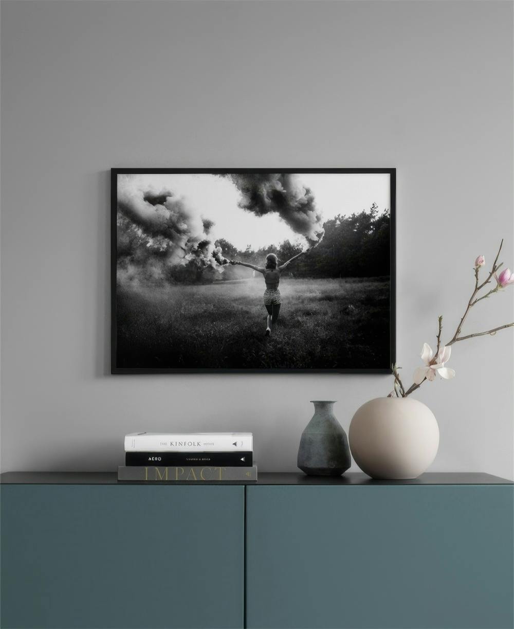 Affiche en noir et blanc dune femme courant dans un champ avec de la fumée, suspendue au-dessus dun buffet.