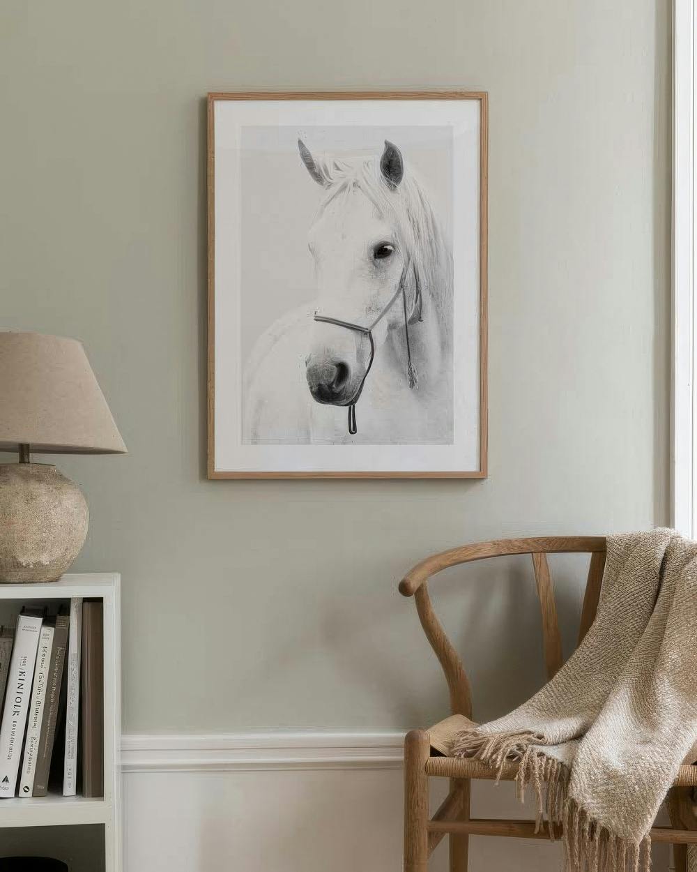 Affiche dun cheval blanc en noir et blanc, accrochée dans un salon moderne au-dessus dune étagère et dune chaise.
