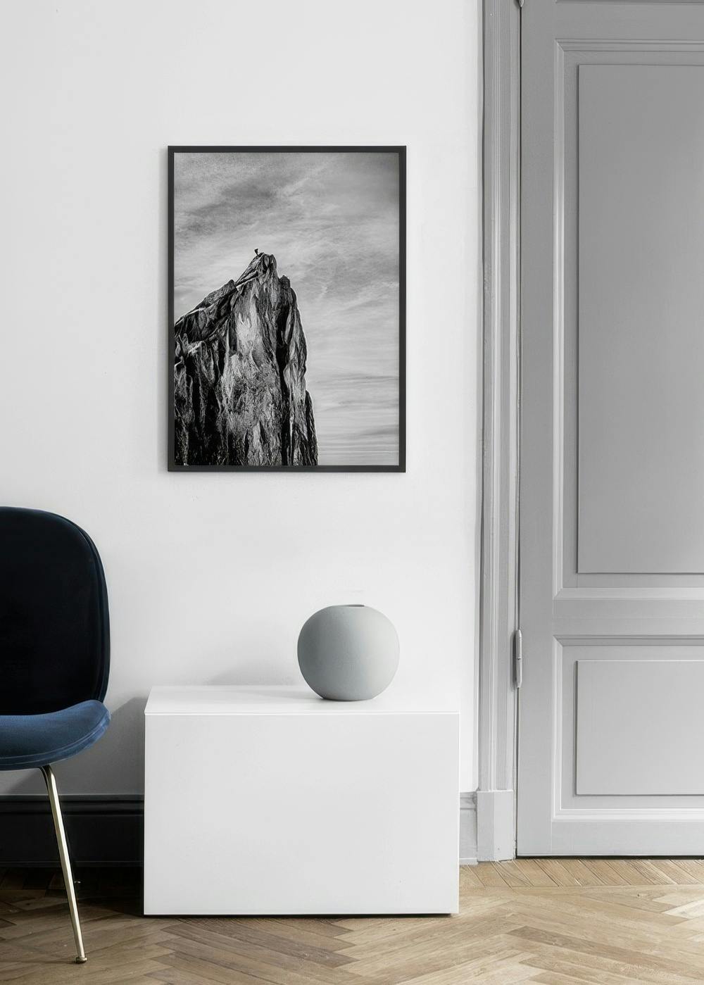 Affiche en noir et blanc d’une falaise rocheuse escarpée sous un ciel nuageux, accrochée dans une pièce lumineuse.