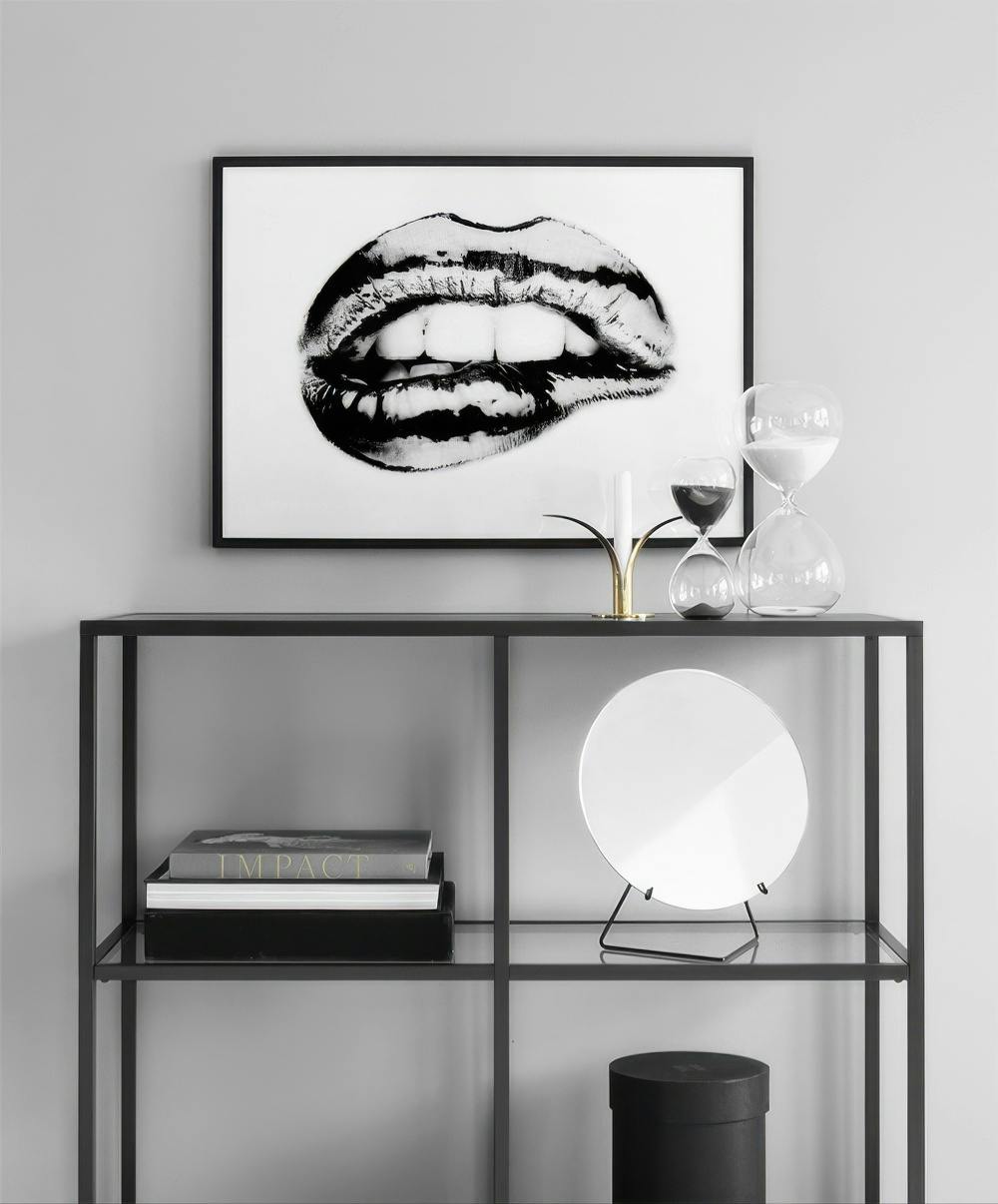 Affiche noir et blanc de lèvres mordançant la lèvre inférieure, affichée sur une étagère contemporaine.